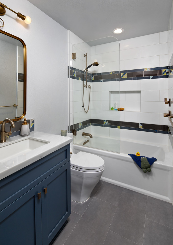 A bathroom with navy blue cabinets and a tile shower.