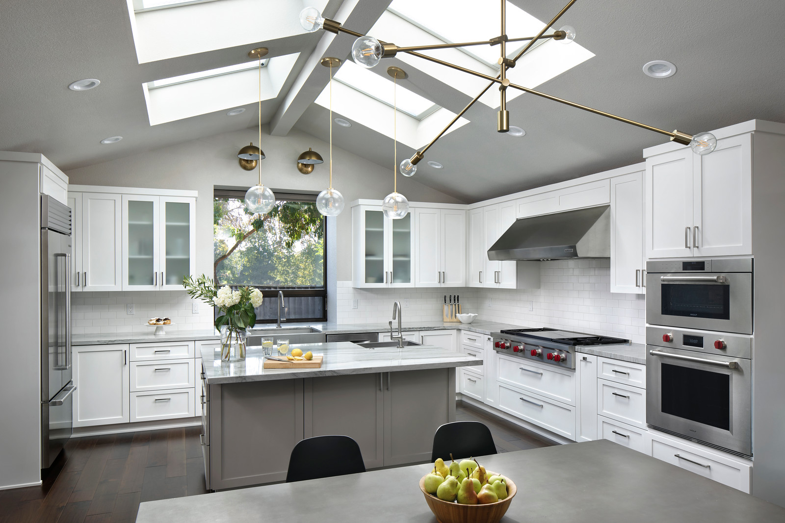 A modern kitchen with grey counter tops, white cabinets, and stainless steel appliances.