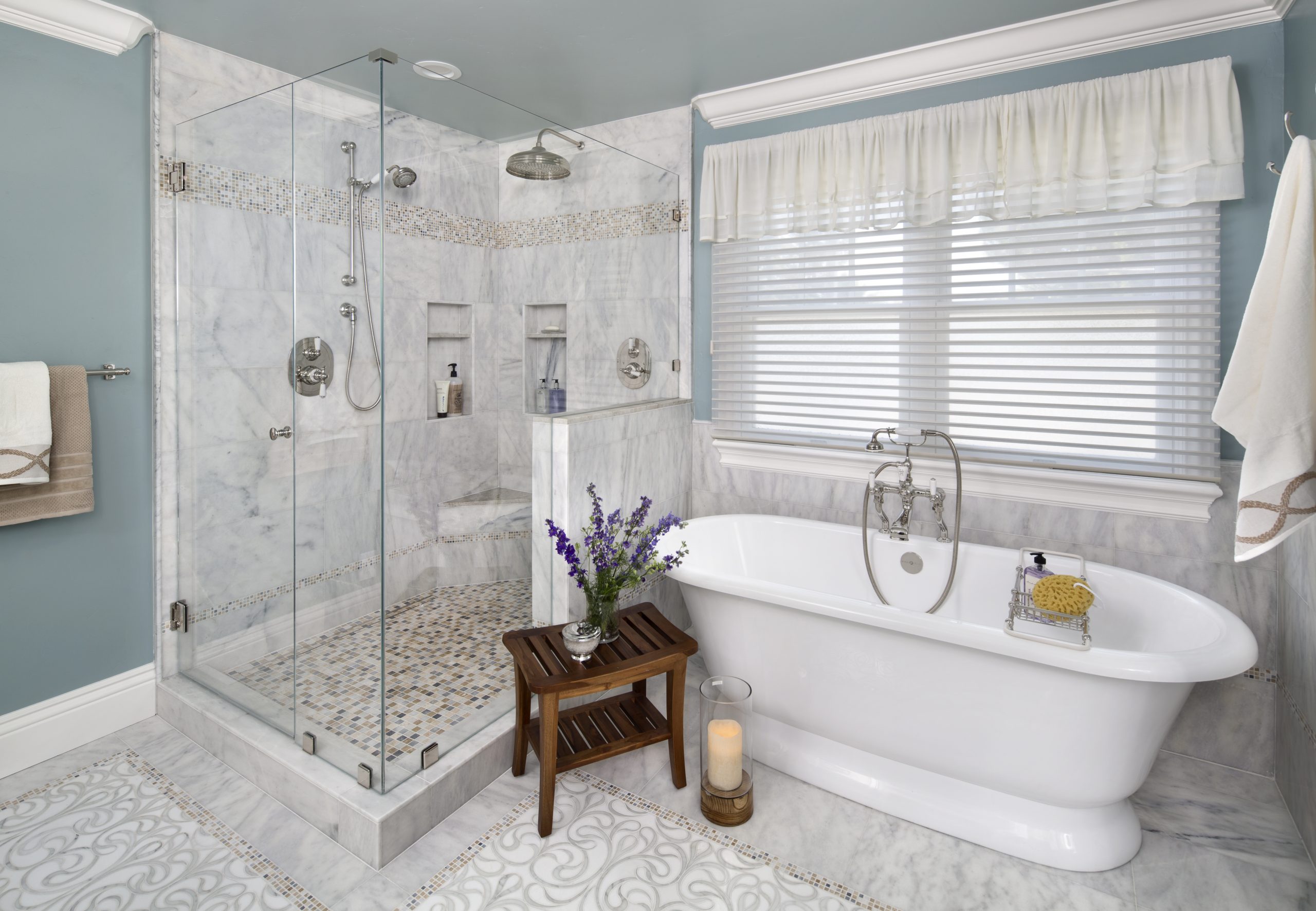 A white porcelain tub with a stone floor shower.