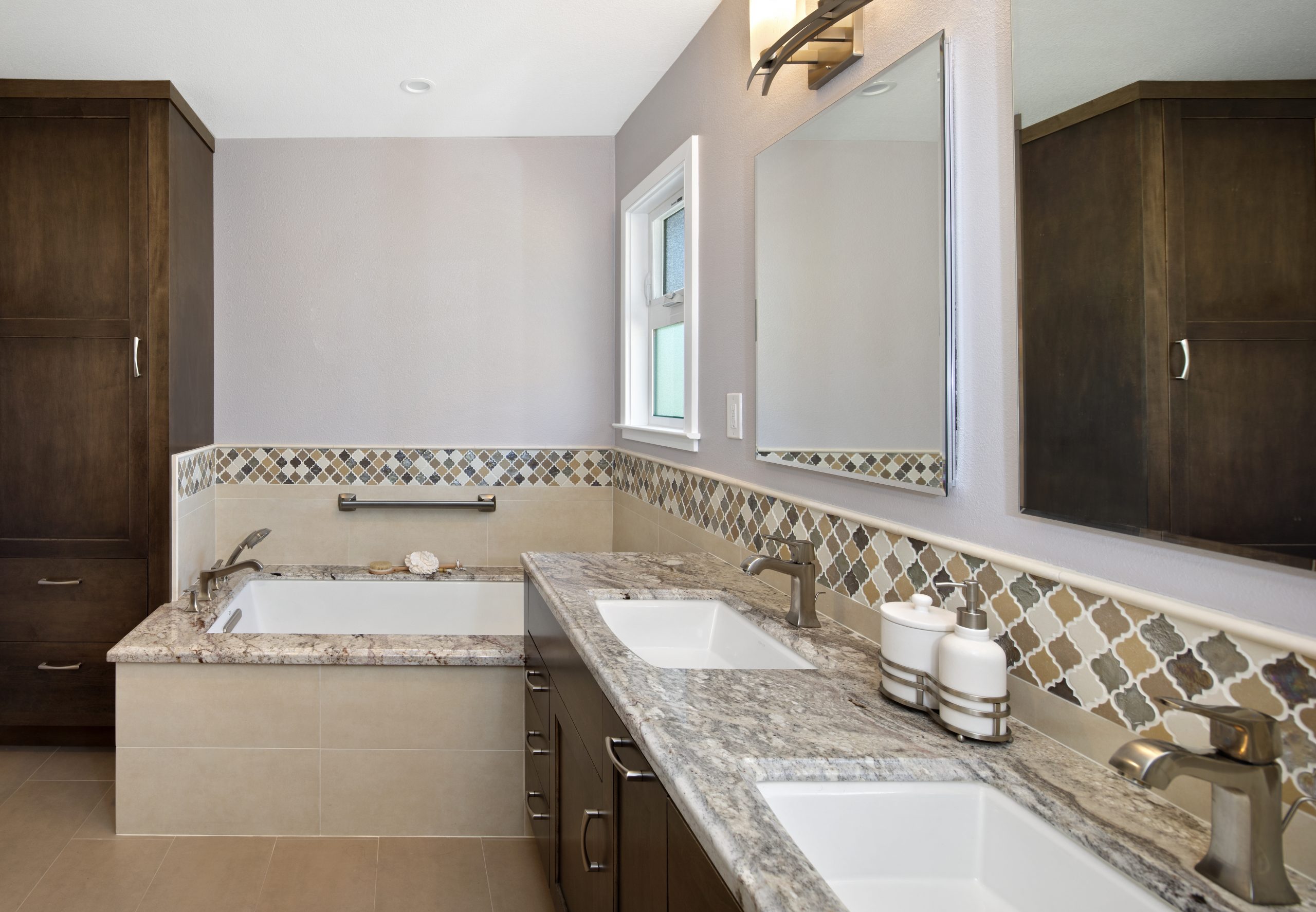 A bathroom with granite counter tops and a granite edged bathtub.