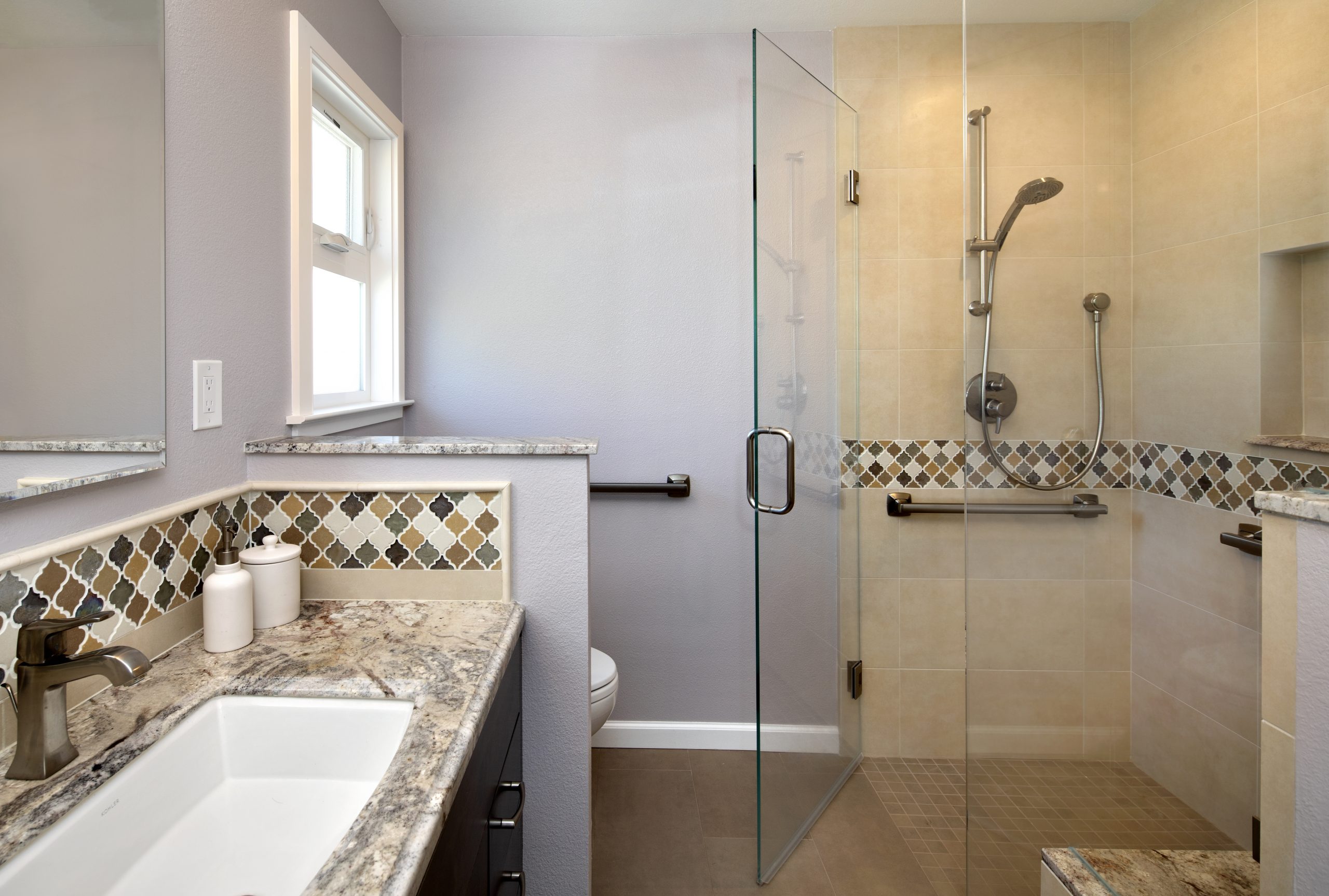 A full glass shower with decorative tile walls.