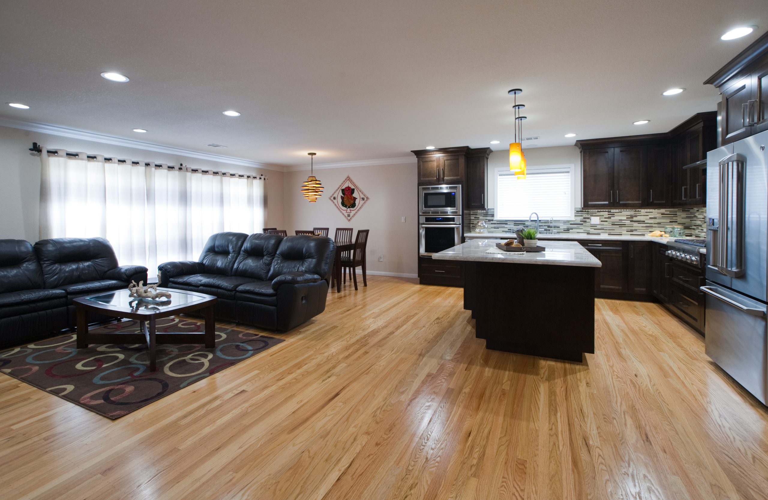 A living room and kitchen remodel with hardwood floors and granite counter tops.