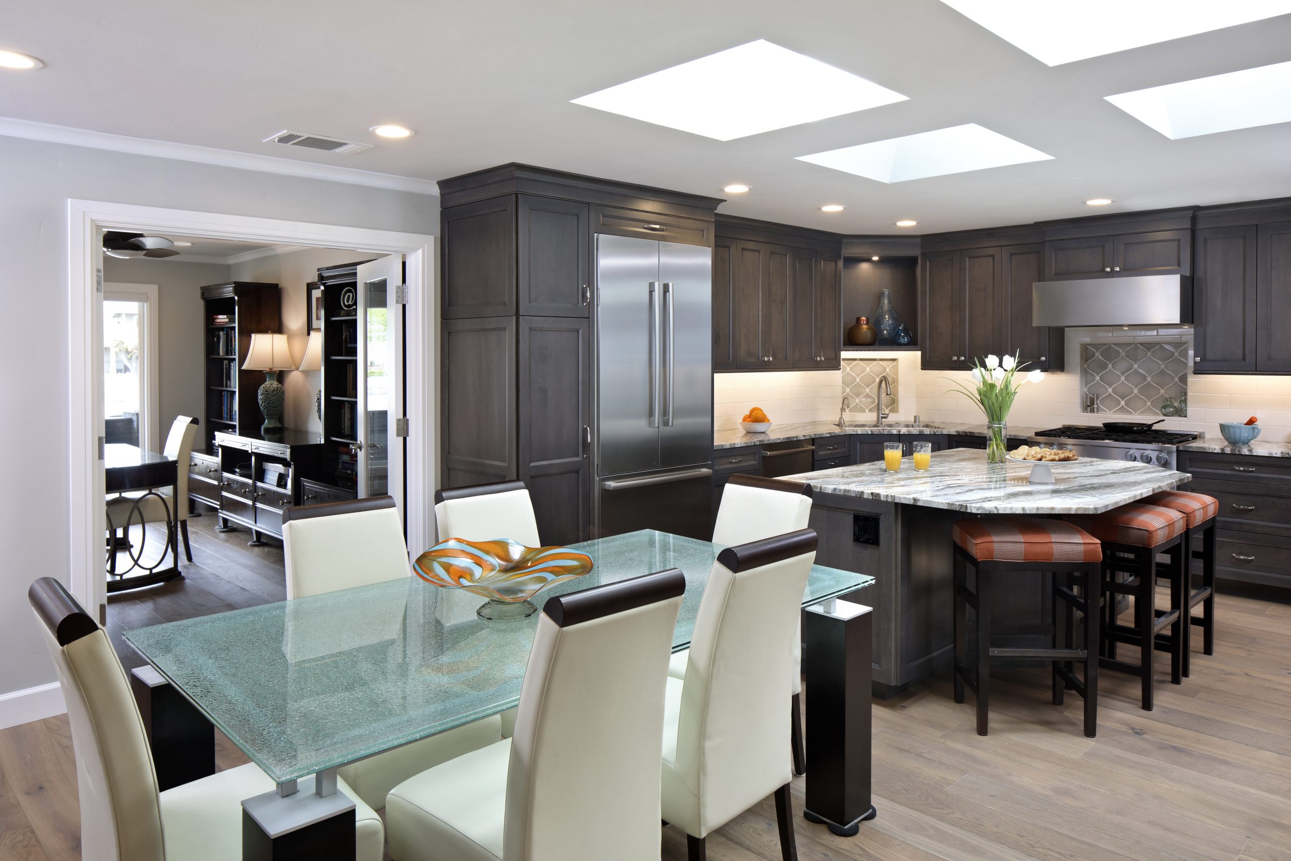 A kitchen and living room combination with a large granite island and glass table.
