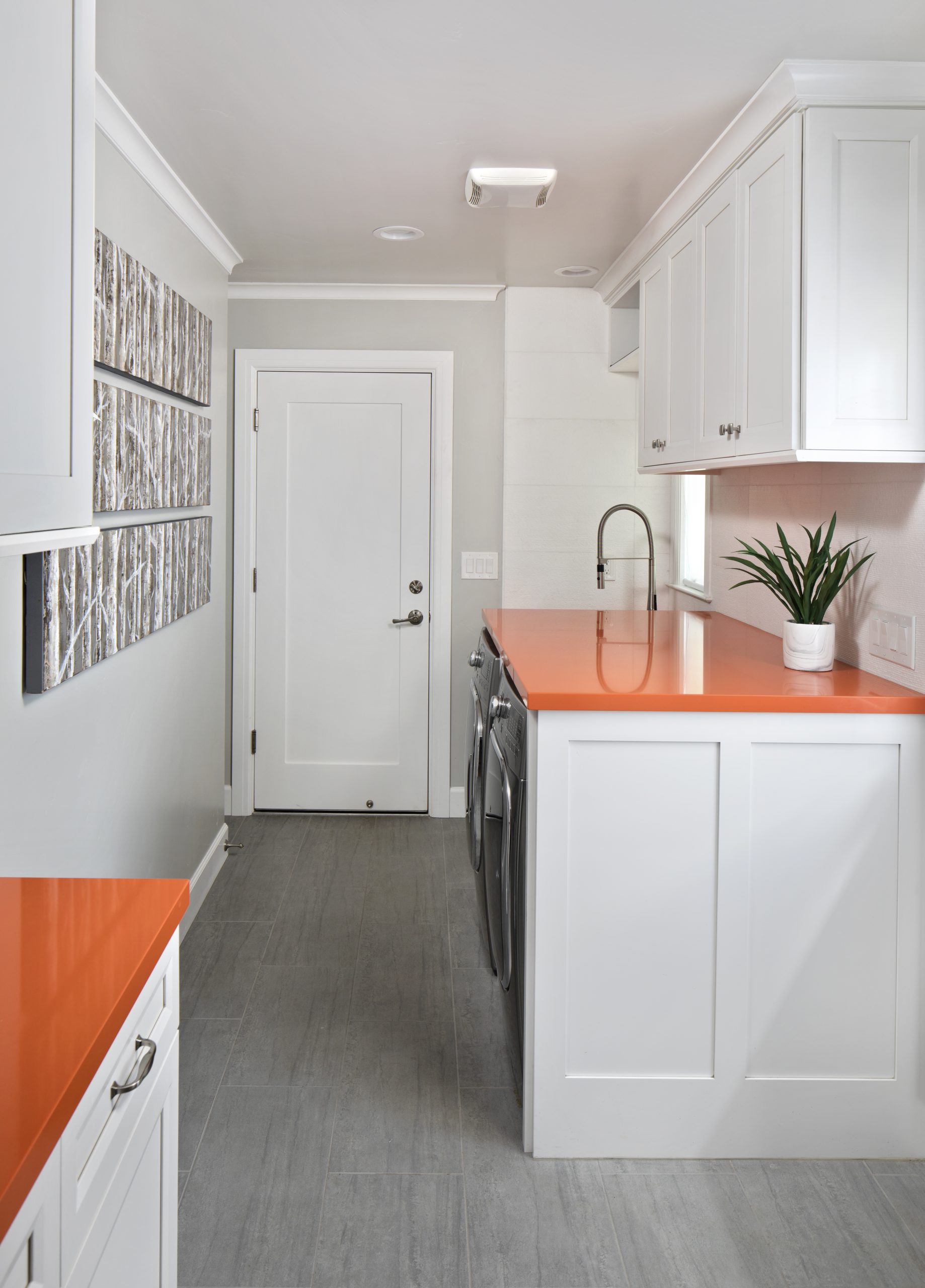 A laundry room with orange counter tops and modern appliances.